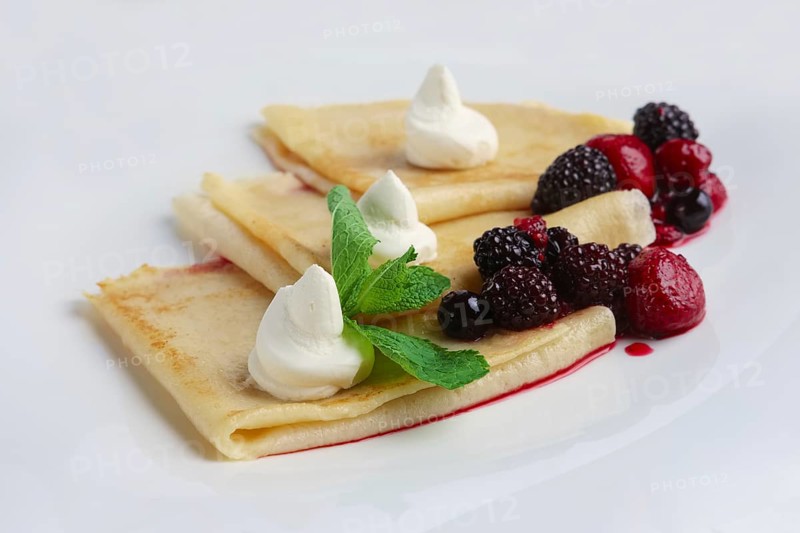 Portion on thin pancakes with sweet cream cheese and berries