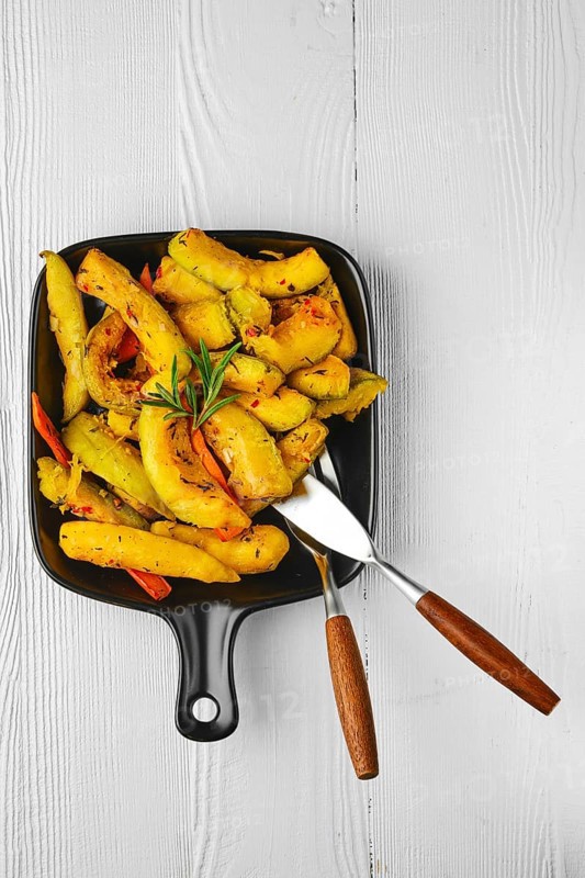 Top view of spicy pumpkin and carrot baked in oven on ceramic plate