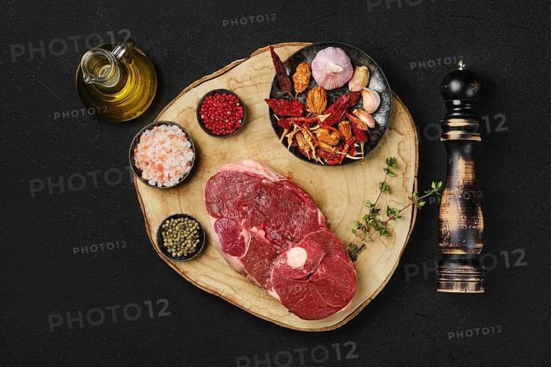 Top view of raw fresh lamb center cut leg steak with spice on wooden slab