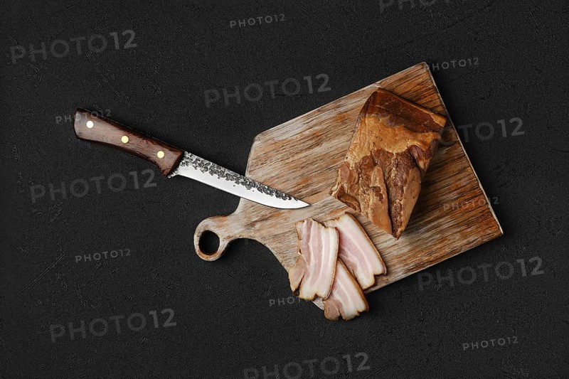 Overhead view of smoked pork bacon with brown bread and eggs on wooden cutting board