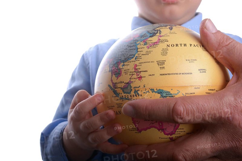 Baby with blue shirt holding a globe in hand on white background