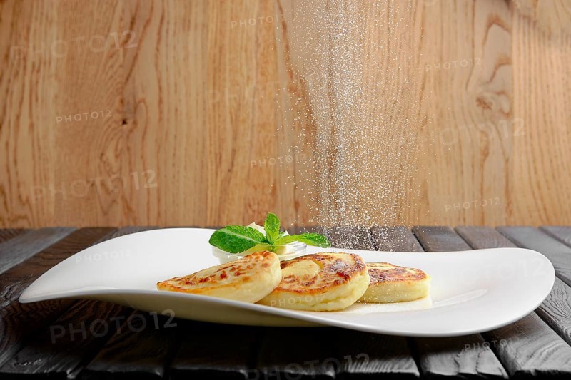 Sprinkling sugar powder from above on cottage cheese curd fritters