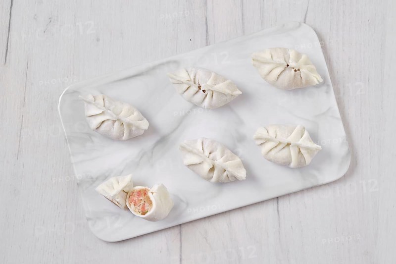 Top view of frozen dumplings stuffed with liver and provencal herbs on marble serving plate