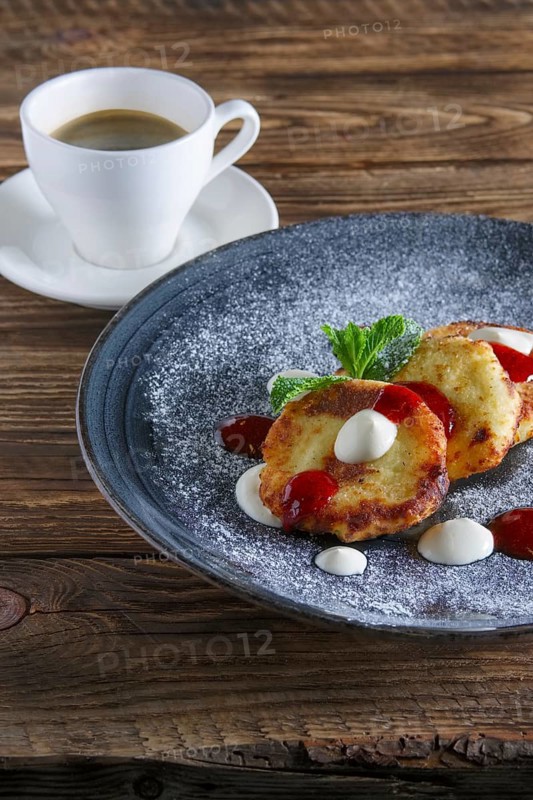 Cheese pancakes served with sour cream and strawberry jam