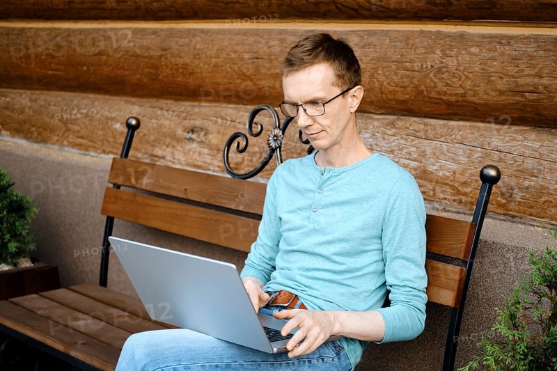 Middle aged man choosing a gift online using laptop outdoors