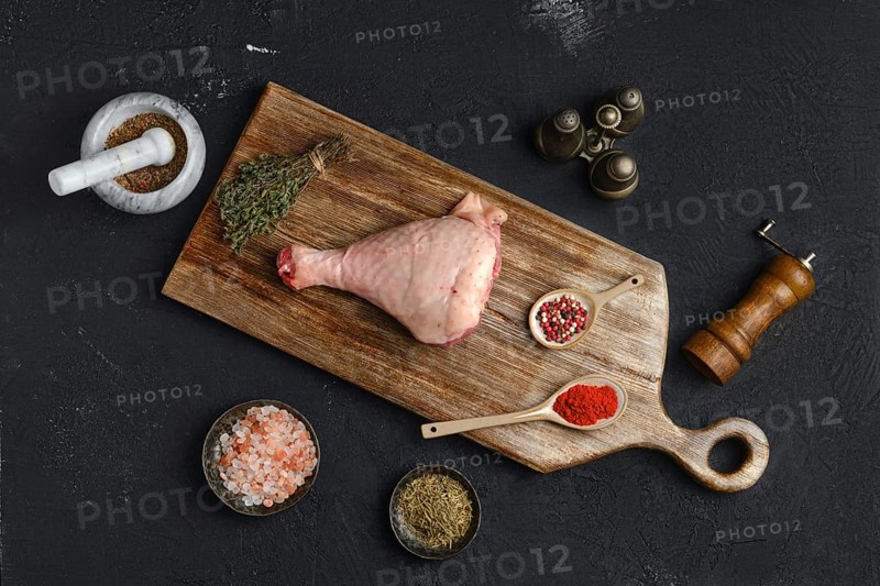 Raw turkey drumstick with skin on wooden board