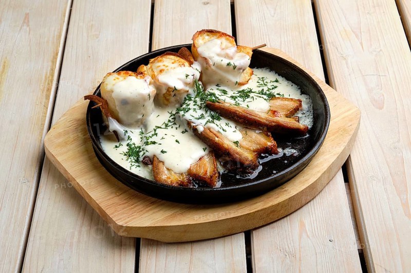 Thin pancakes on skewer stuffed with cheese and served with fried bacon