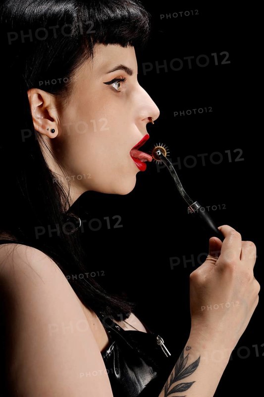 Woman with Wartenbergrad on her tongue in vinyl and latex outfit