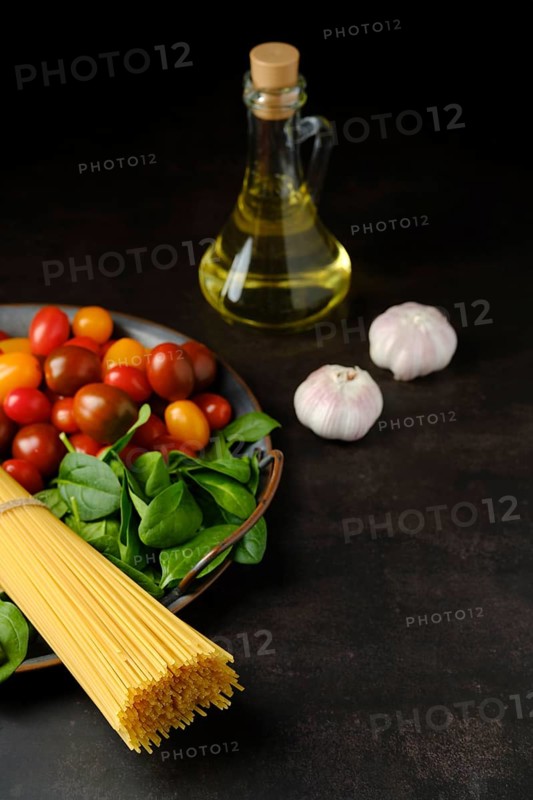 Low key photo of bunch of raw spaghetti with spinach