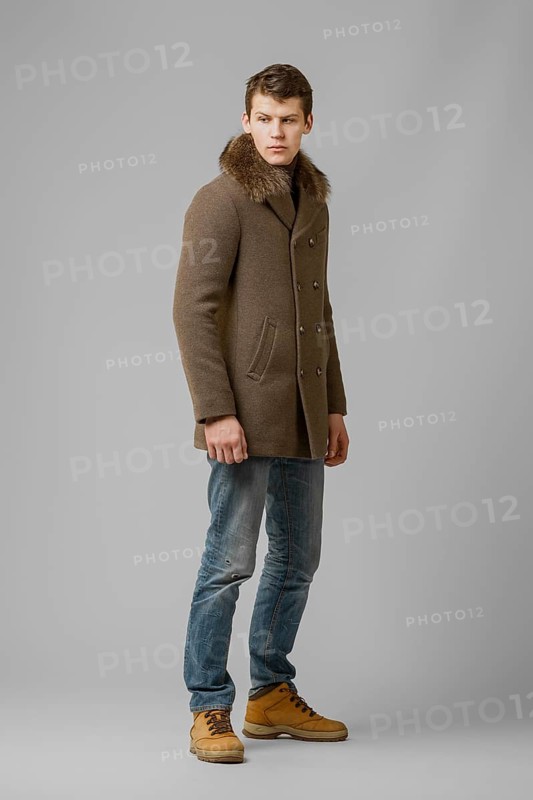 Full length portrait of handsome man in warm winter coat posing in studio