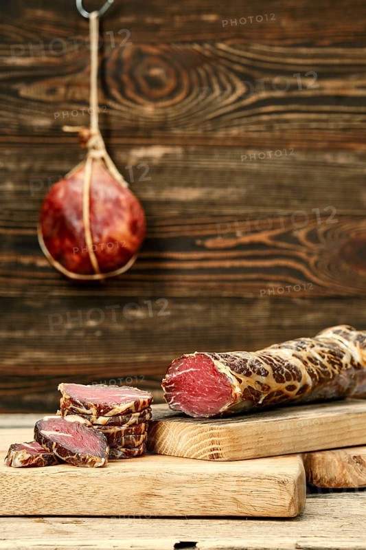 Smoked dried beef meat cut on slices on wooden cutting board