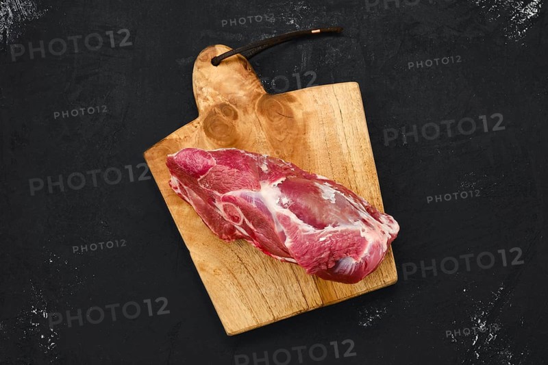 Overhead view of raw lamb rump on wooden cutting board
