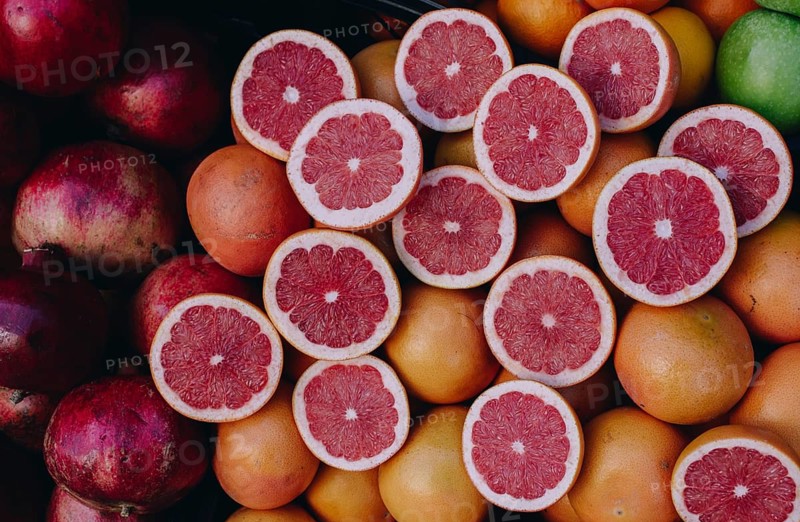 Cut in halves grapfruits alongside pomegranates on display