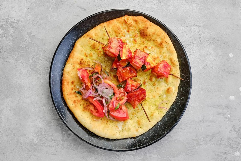 Top view of shashlik served on tortilla with tomato and red onion