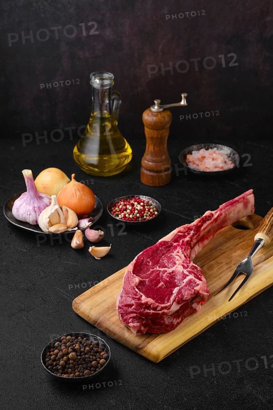 Raw beef cowboy steak with spice and seasoning ready for cooking