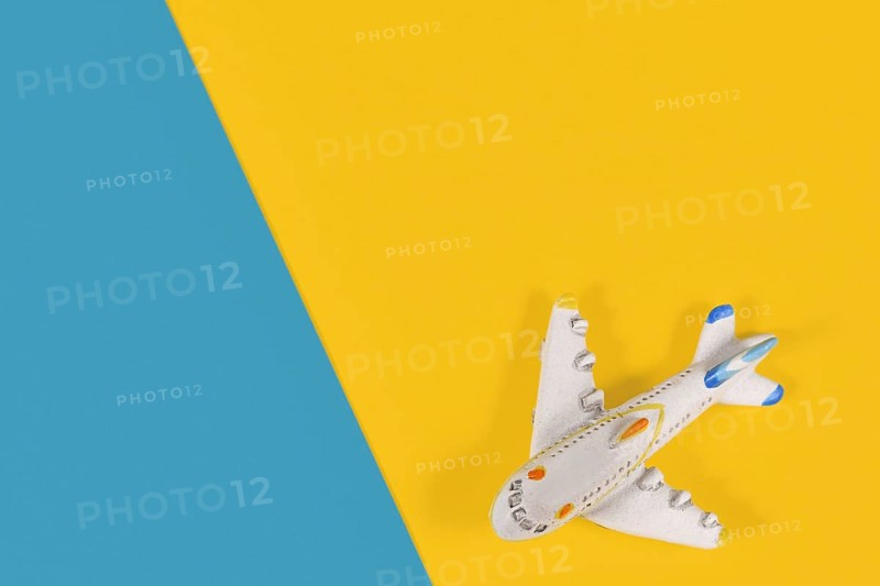 Small model airplane in corner of yellow and blue background