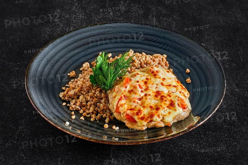 Chopped pork meat baked with cheese and tomato served with buckwheat porridge