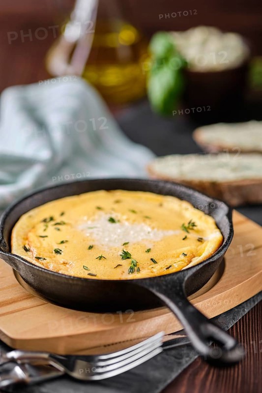 Omelette in cast iron skillet with bread and herbal butter
