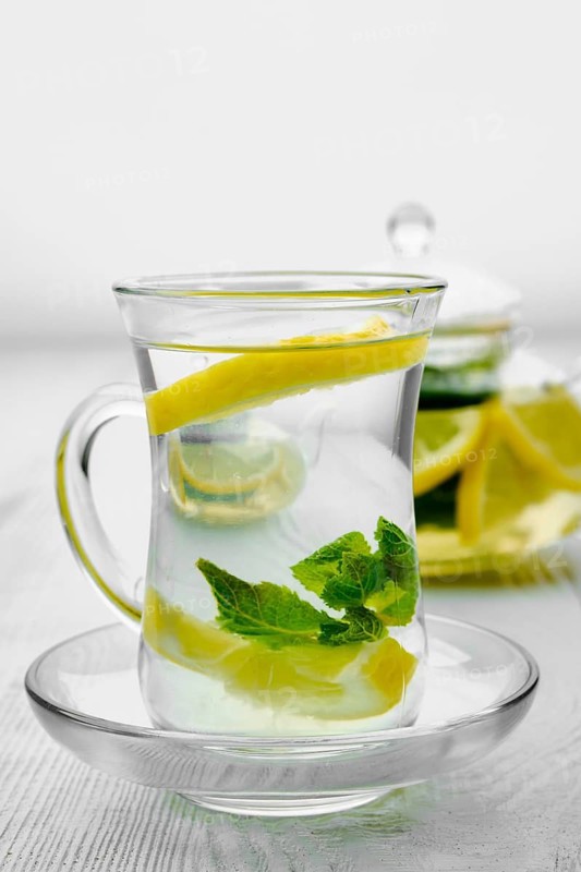 Antioxidant hot drink with lemon and mint in transparent tea pot and glass