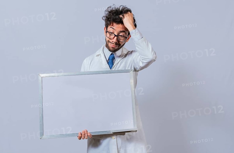 Male scientist in white coat holding and pointing at a blank whiteboard. Disheveled-haired man holding blank whiteboard