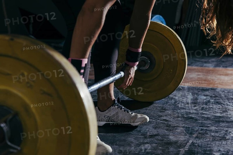 Fitness concept with woman touching barbell