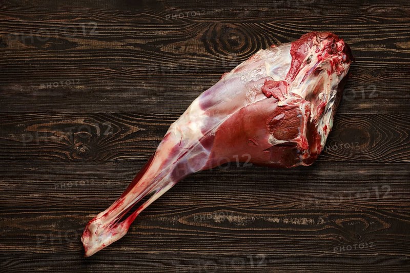 Overhead view of raw deer leg over wooden background