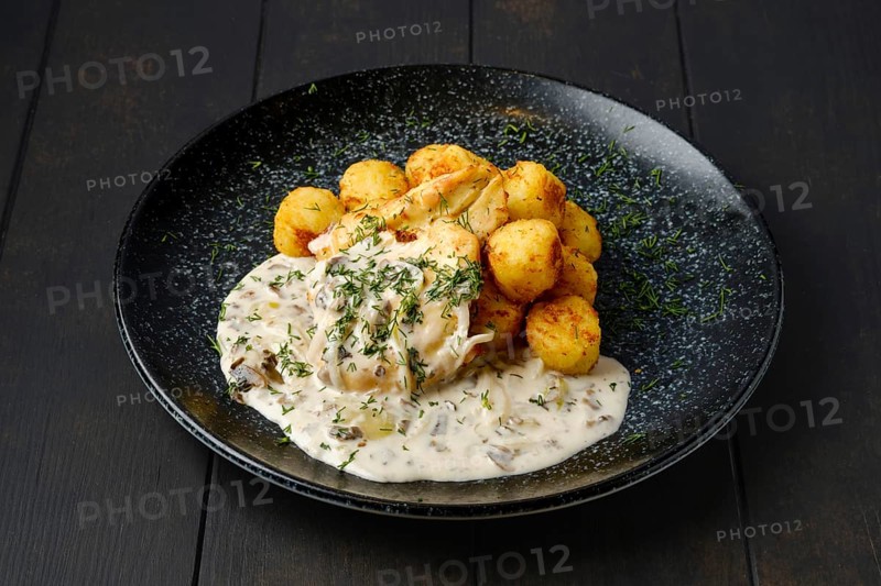 Fried zander fillet with mushroom sauce and potato balls on a plate