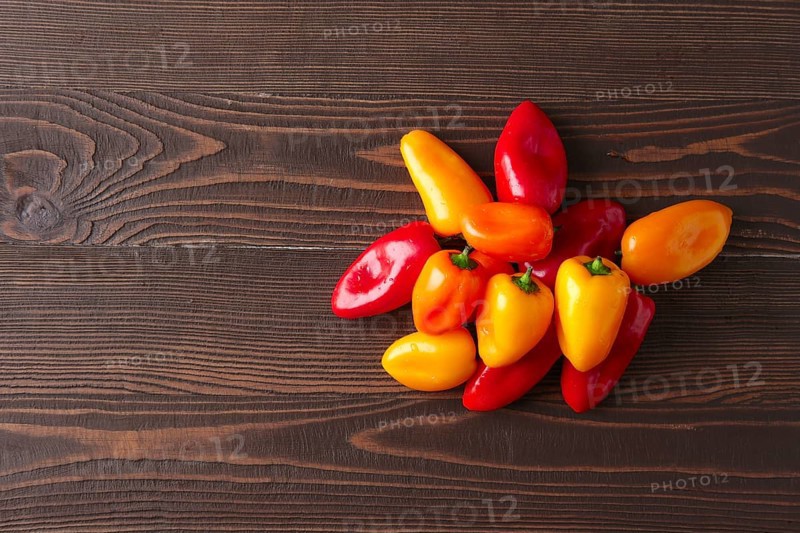 Sweet mini peppers sorted by color natural wooden background