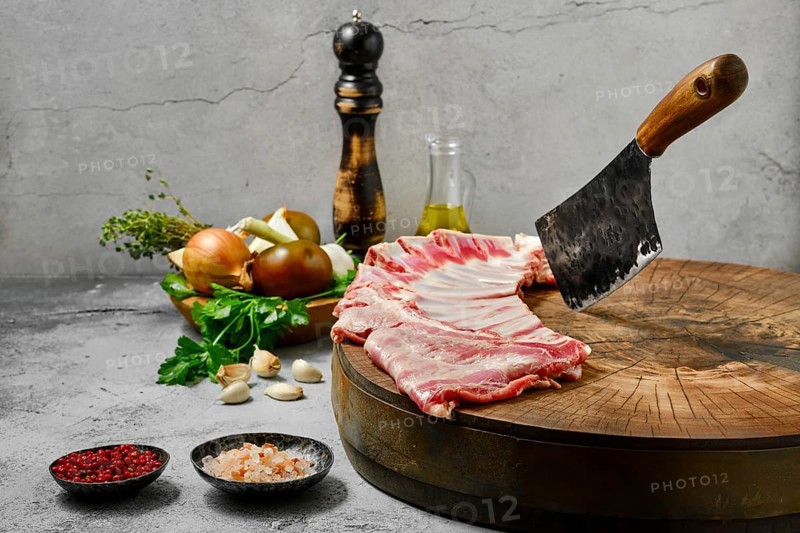 Uncooked lamb flap ribs with ingredients on wooden log