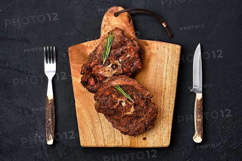 Top view of grilled lamb neck on wooden cutting board