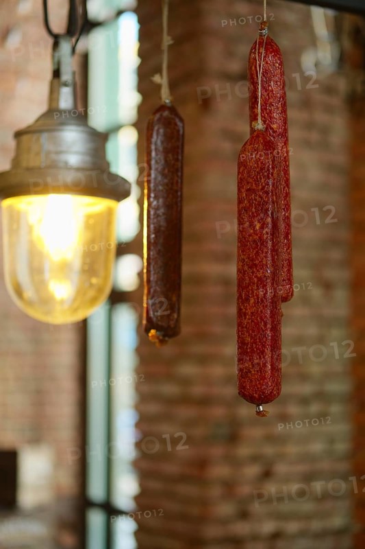 Smoked sausagees hanging on a hook under the ceiling. Photo with shallow depth of field