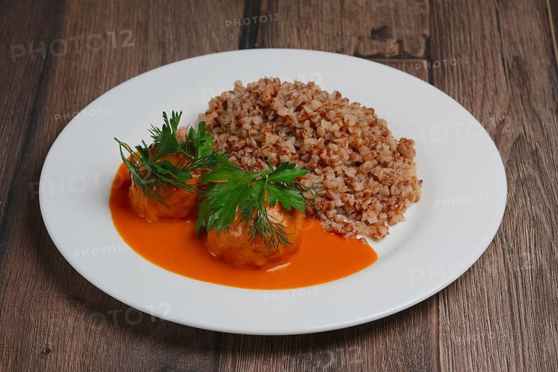 Buckwheat porridge and meatballs on wooden table