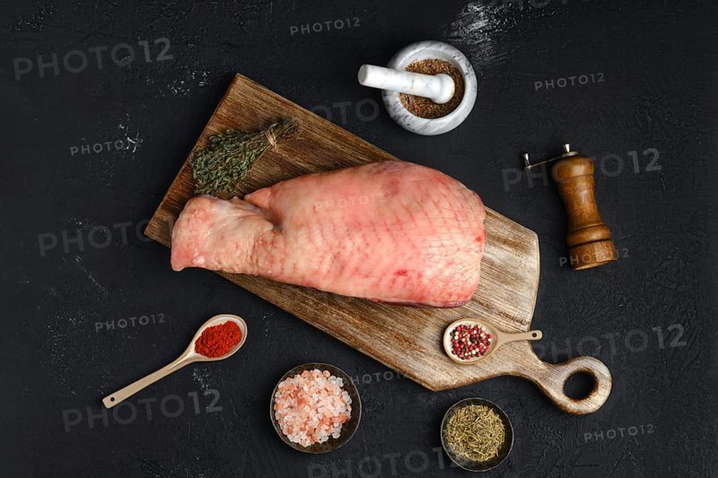 Top view of raw half of turkey breast with bone and skin on dark background