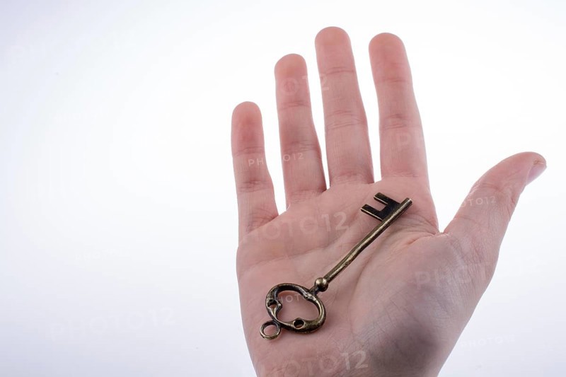 Hand holding a retro styled metal key on a white background