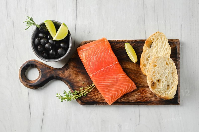 Top view of piece of fresh salmon steak with ciabatta and spicy herb sauce