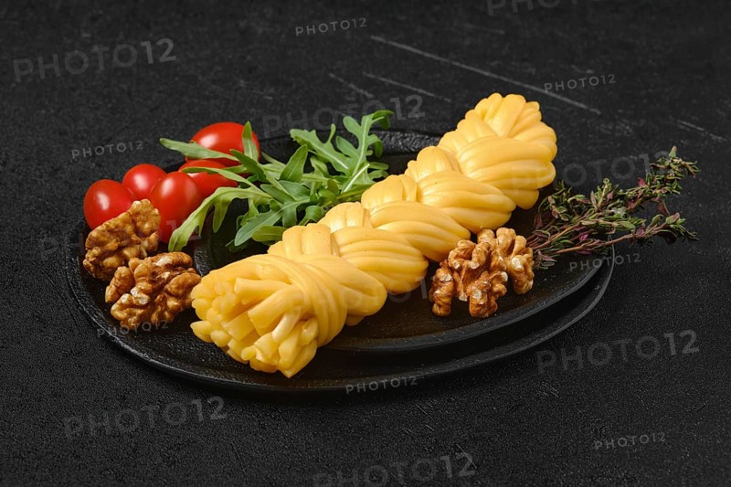 Smoked braided cheese with walnuts and tomatoes on a plate