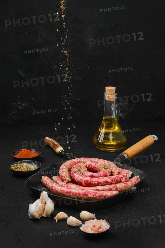 Sprinkling thin beef sausages with spice rub on grill pan