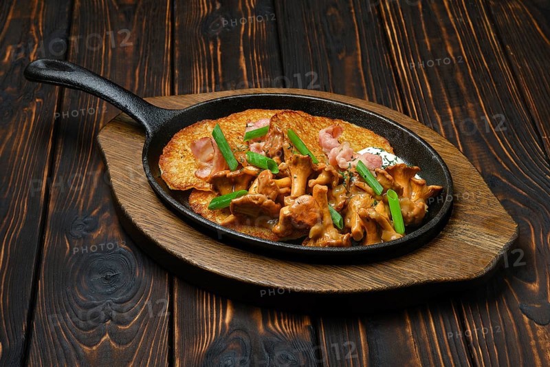 Potato pancakes with chanterelles and pork in cast iron skillet