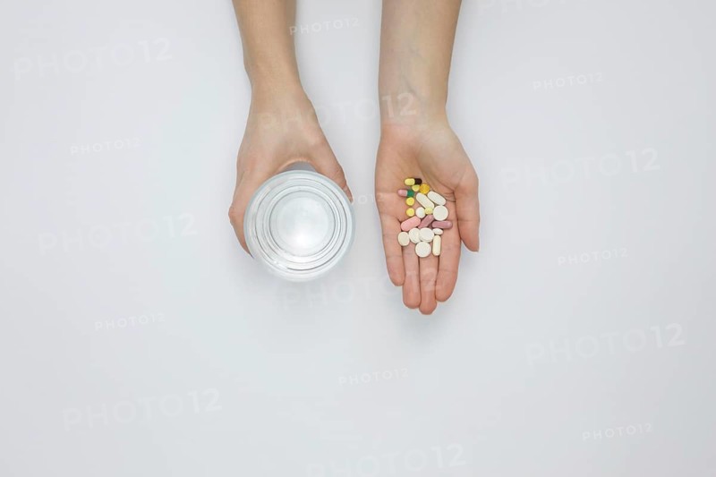 Flat lay hand holding pills glass water