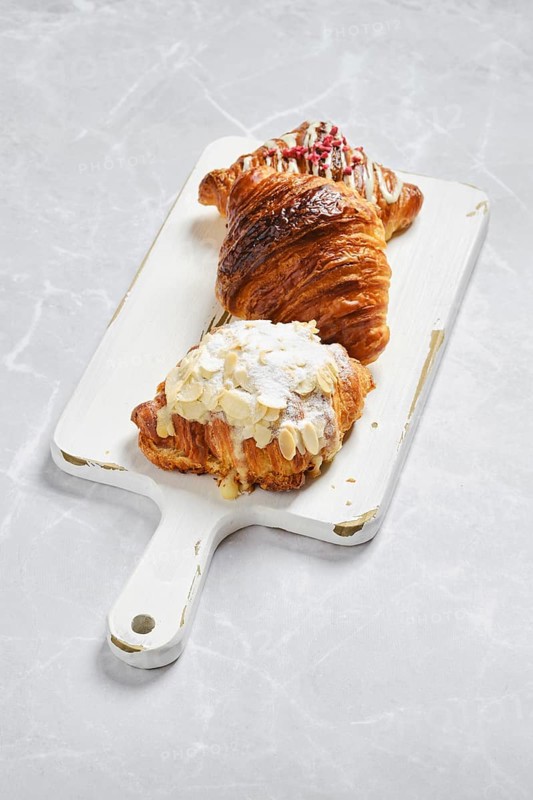 Various croissants on white serving board on marble background