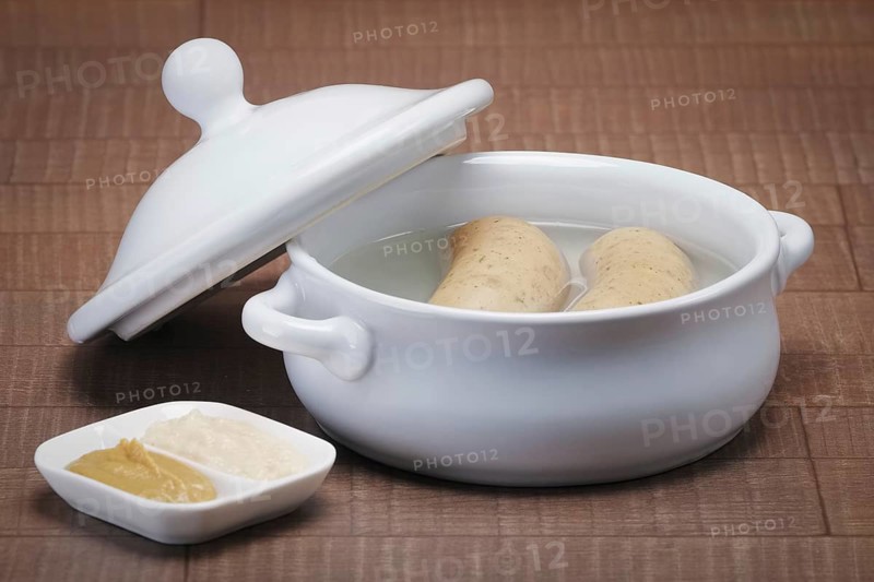 Pot with homemade sausage in broth served with mustard and horseradish