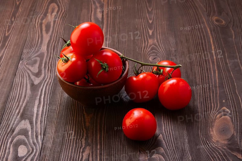 Branch of fresh tomatoes on wooden table