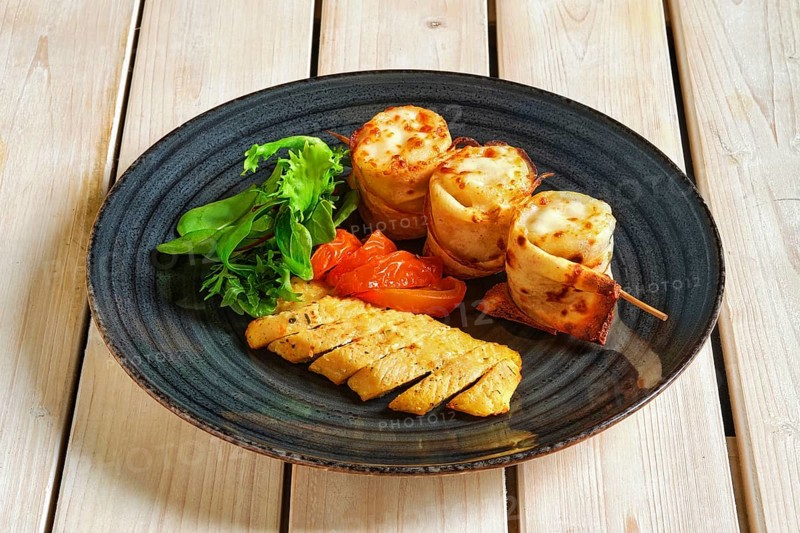 Thin pancakes stuffed with soft cheese rolled and put on skewer