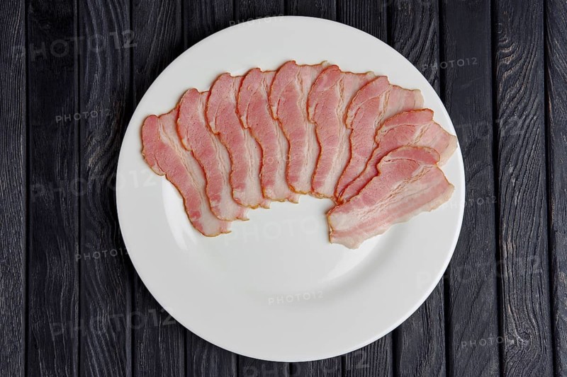Top view of plate with slices of fresh bacon