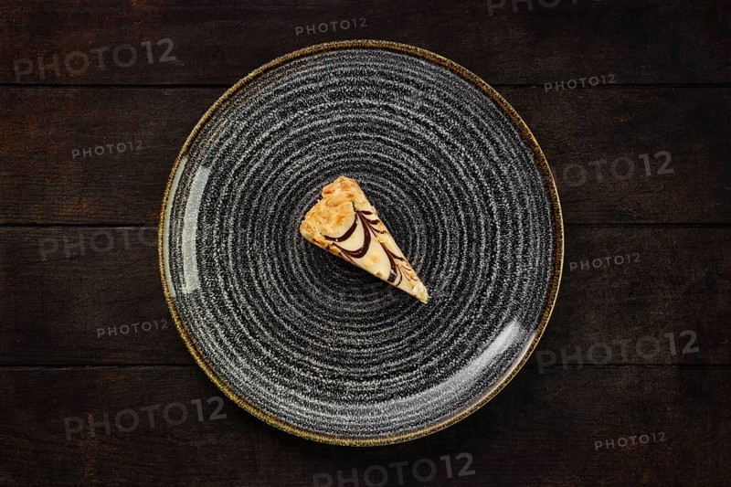 Top view of plate with piece of peanut cake on wooden background
