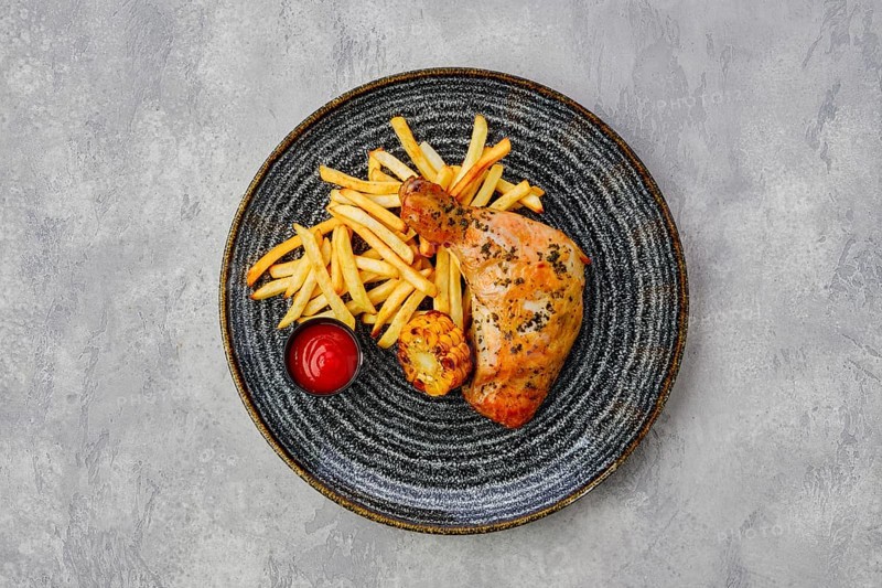 Top view of baked chicken thigh with french fries