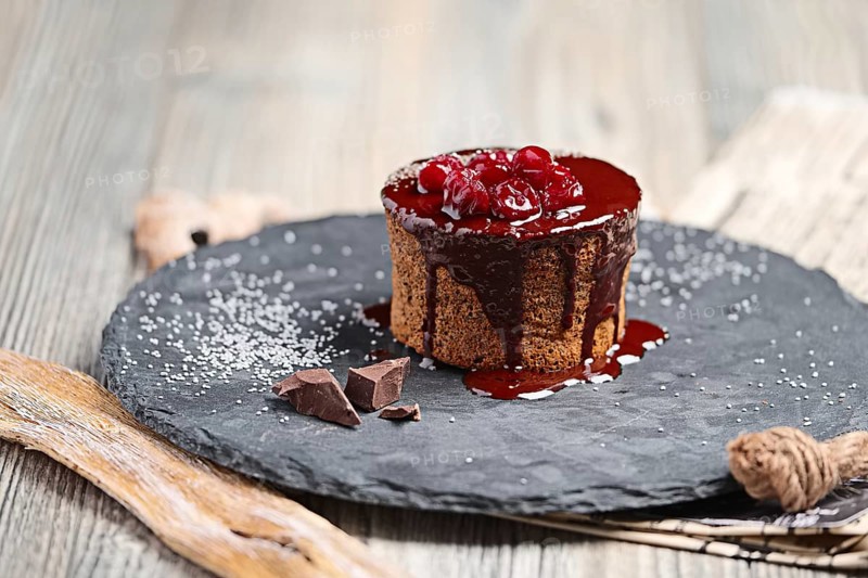 Cake with cherry and chocolate syrup on wooden table