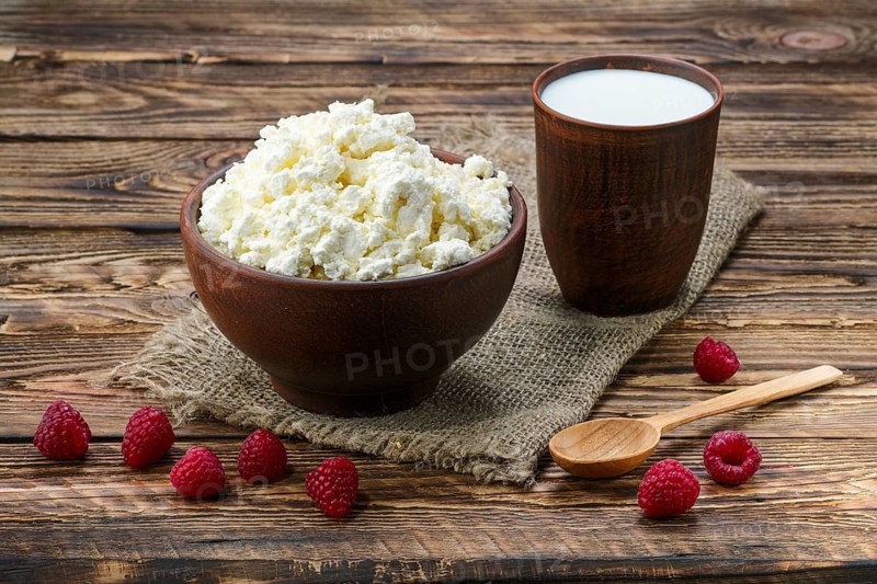 Cottage cheese and milk in clayware on wooden table