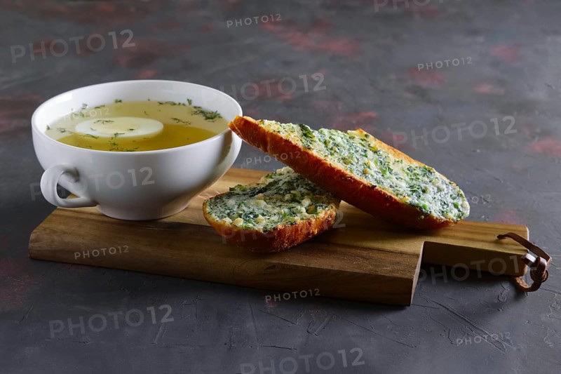 Clear chicken broth with egg served with toasts