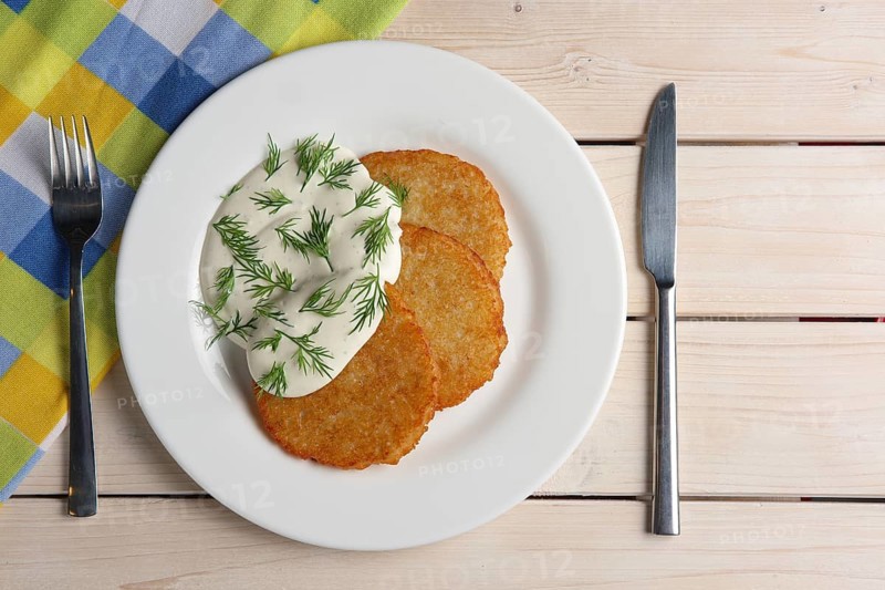 Draniki with sour cream on wooden table